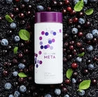 A white bottle of Nutra-Max dietary supplement with a purple cap, surrounded by dark berries and blueberries on a dark background.